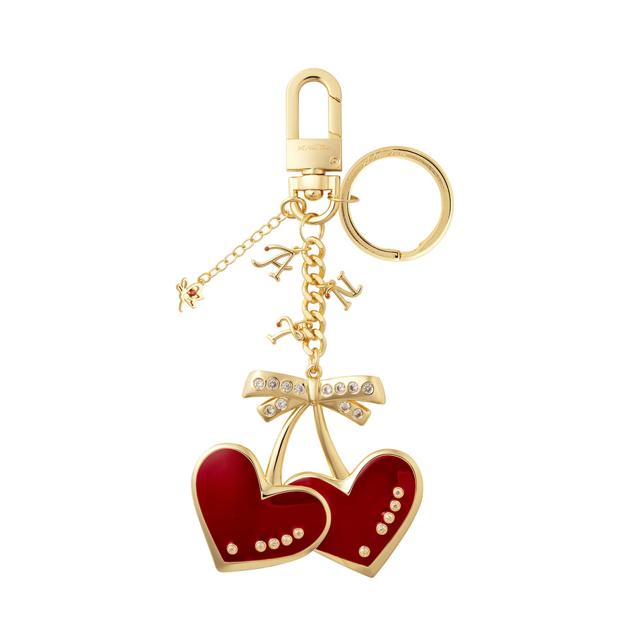 Gold keychain with red heart-shaped charms and a bow on a white background