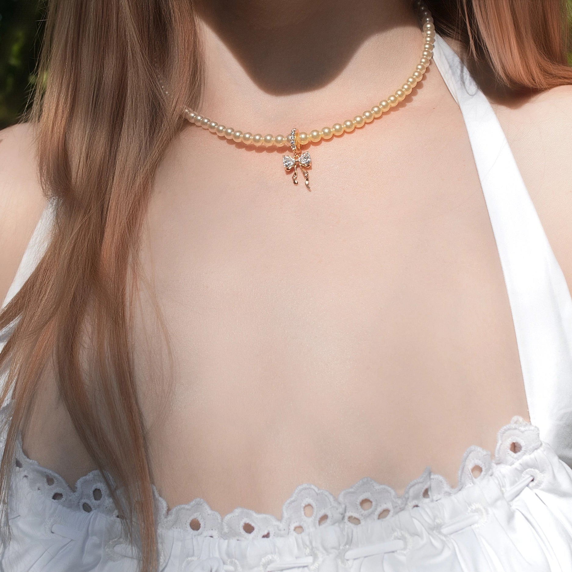 Pearl necklace with a butterfly pendant on a person's neck