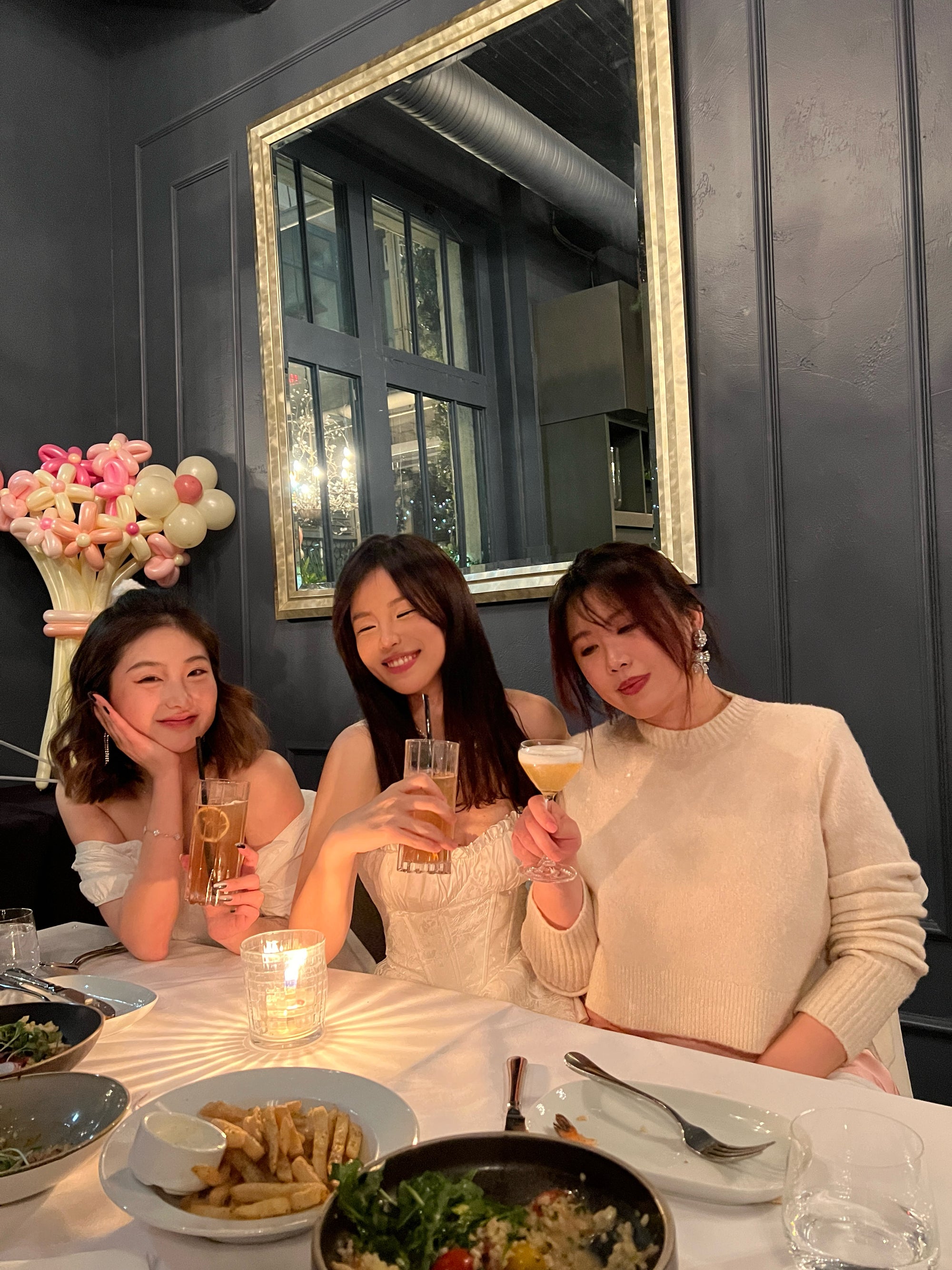 Three co-founders sitting at a table with food and drinks, smiling and posing for a photo.