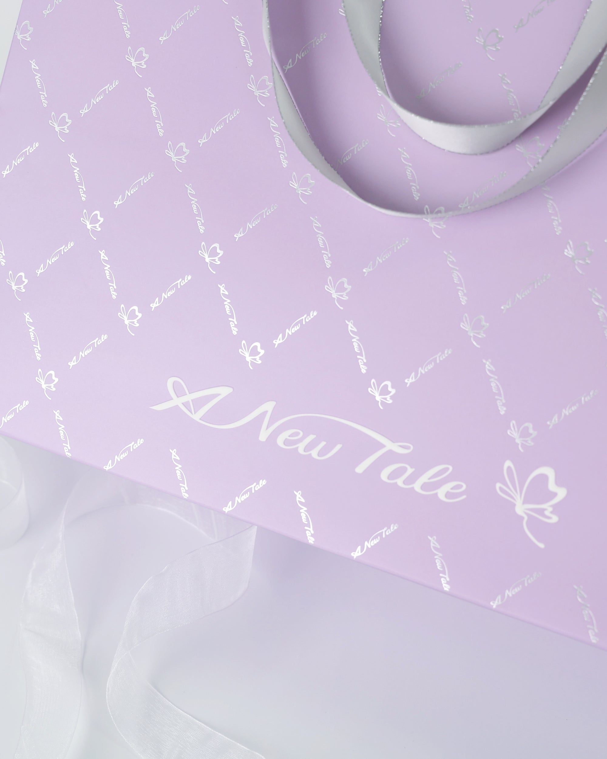 A close up A New Tale signature gift bag with butterfly patterns on a light gray background
