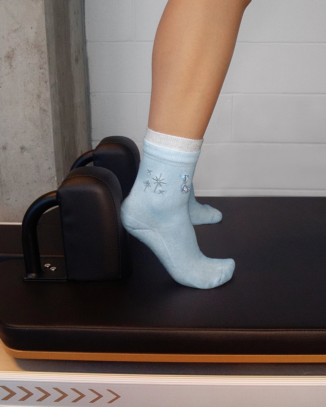 Person using a Pilates reformer machine with a neutral background