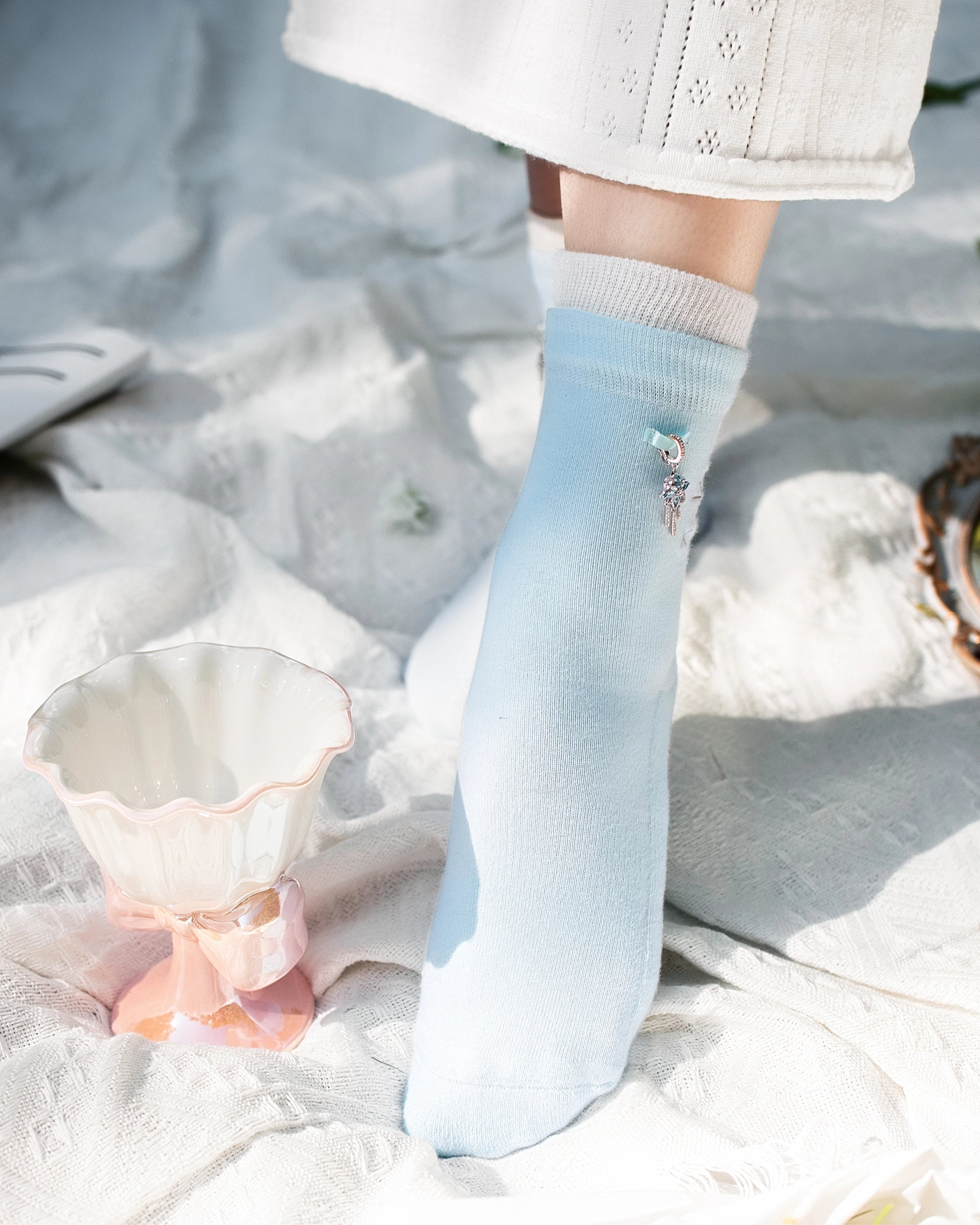 Light blue ankle sock with decorative element worn by a person on a snowy ground.